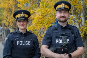 Two RCMP officers in new navy-blue uniform shirts and police vests standing outdoors. Photo: BC RCMP