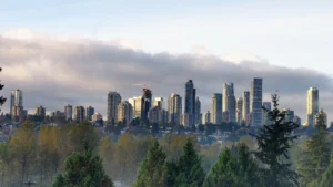 High-rise towers of Burnaby's Metrotown skyline rising above trees under a cloudy sky