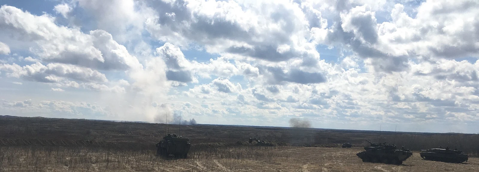 Armoured vehicles on a live-fire training range at CFB Wainwright under a cloudy sky