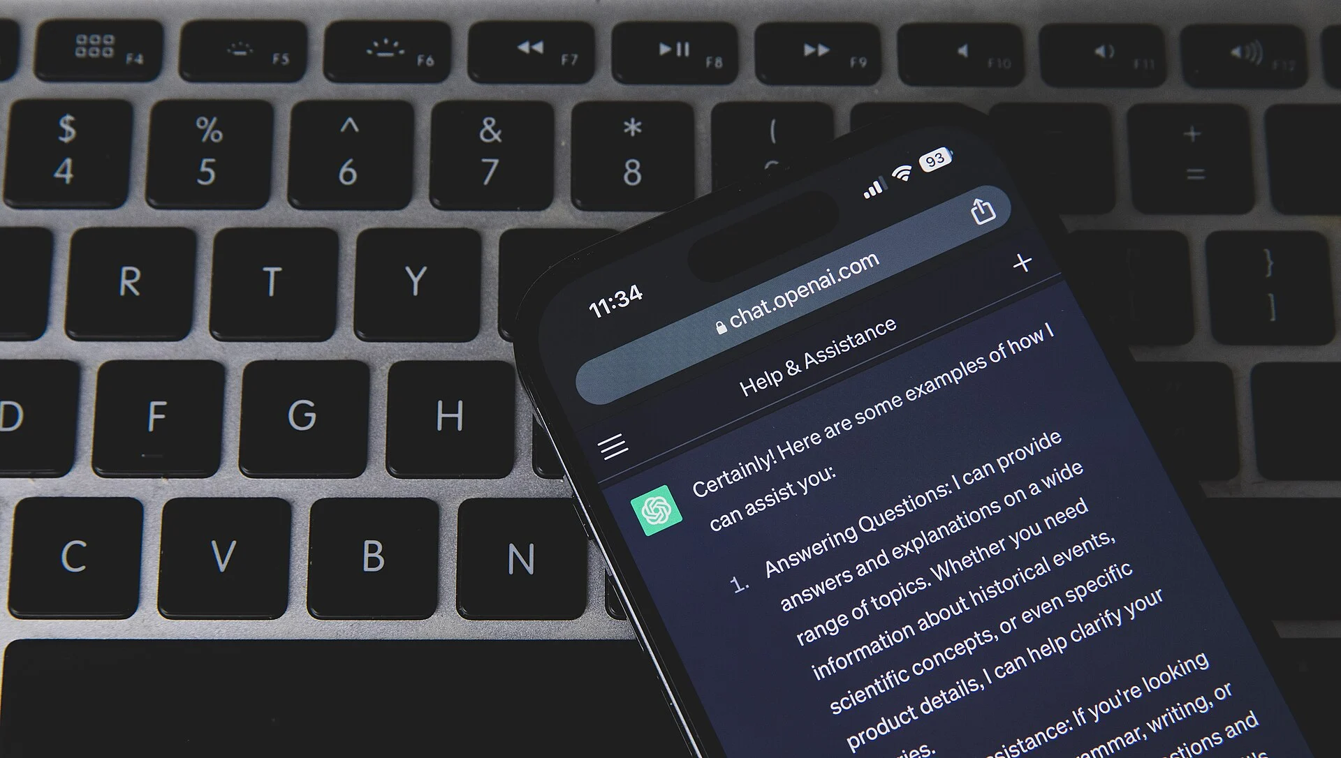 Phone showing a ChatGPT conversation resting on a laptop keyboard