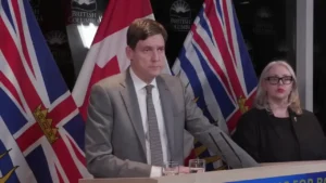 BC NDP Leader David Eby speaking at a podium in front of British Columbia and Canada flags, in a file photo