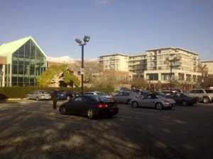 A parking lot with rows of parked cars and apartment buildings behind