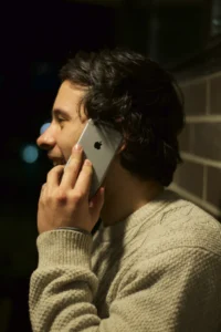 A man in profile holding a smartphone to his ear during a phone call