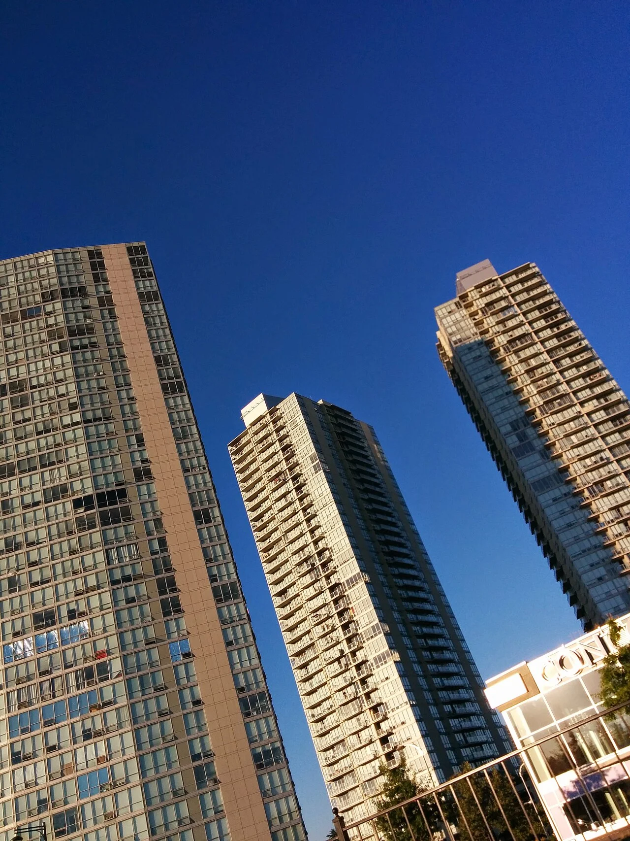 Three residential towers in Surrey photographed from below against a blue sky